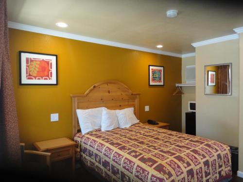 - une chambre avec un lit et un mur jaune dans l'établissement Colusa Motel, à Colusa