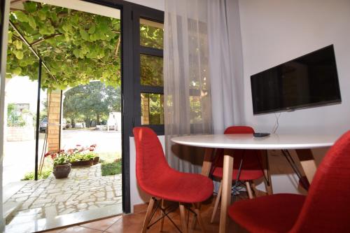 a dining room with a table and red chairs at Apartments Pavić Valbandon in Fažana