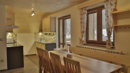 a kitchen with a wooden table and a window at Horský apartmán Draps in Ostružná