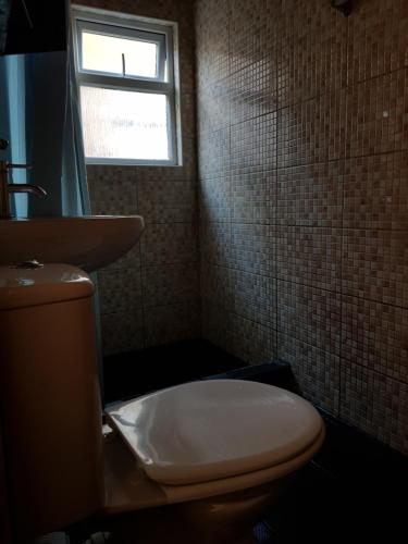 a bathroom with a toilet and a sink and a window at Cozy Guest House in Luton