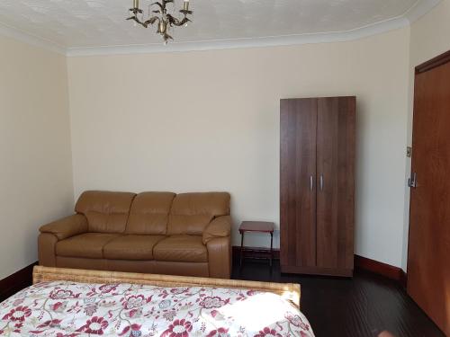 a living room with a couch and a bed at Cozy Guest House in Luton
