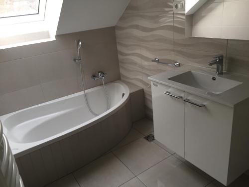 a bathroom with a bath tub and a sink at Kirhouse Apartment in Bohinjska Bela