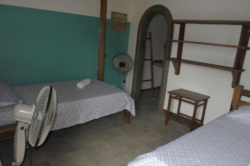 a room with two beds and a fan in it at Wild Waves Surf-House in Popoyo