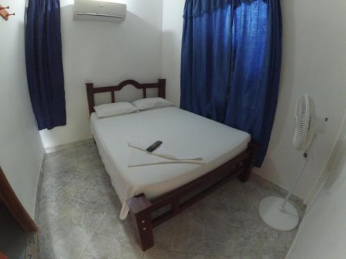 a bedroom with a bed with blue curtains and a fan at Hospedaje la Glorieta in Santa Fe de Antioquia