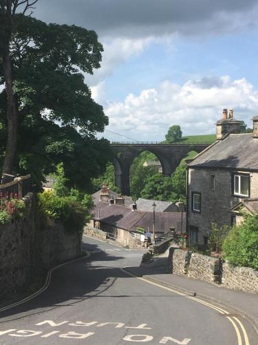 an empty road in a village with a bridge in the background at Inglenook Guest House in Ingleton 