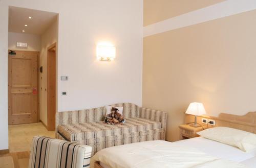 a bedroom with a couch and a bed in it at Hotel Rifugio Solander in Commezzadura