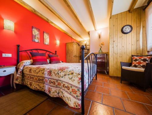 a bedroom with red walls and a bed and a chair at Apartamentos Rurales L´Abiseu in Caboalles de Abajo