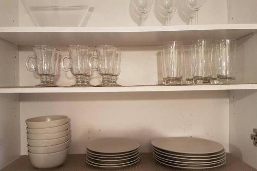 a shelf filled with glasses and plates and cups at 2-Bedroom Apartment Sweet #1 by Amazing Property Rentals in Gatineau