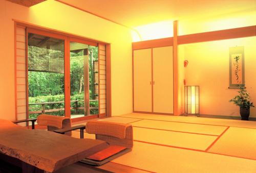 a room with a table and chairs and a window at Hanafubuki in Ito