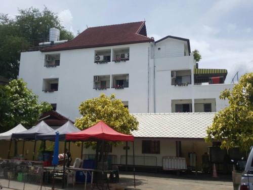 een wit gebouw met tafels en parasols ervoor bij V.I.P. House in Chiang Mai