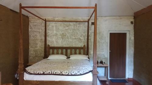 1 dormitorio con cama con dosel y almohadas blancas en Raj Estate Stay en Madikeri
