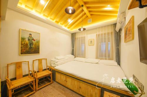 a bedroom with a large bed and two chairs at Pipa Hotel Datong in Datong