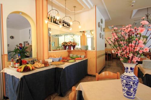 a table with plates of food and a vase with flowers at Hotel Moby Dick in Rimini