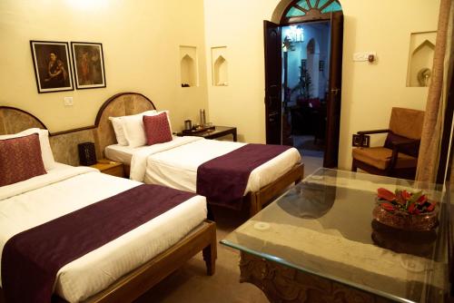 ein Hotelzimmer mit zwei Betten und einem Glastisch in der Unterkunft Panchkote Raj Ganges in Varanasi