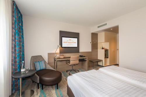 a hotel room with a bed and a desk and a tv at Hotel Scheffelhöhe in Bruchsal