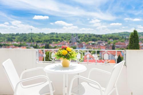 a white table with a vase of flowers on a balcony at Hotel Scheffelhöhe in Bruchsal