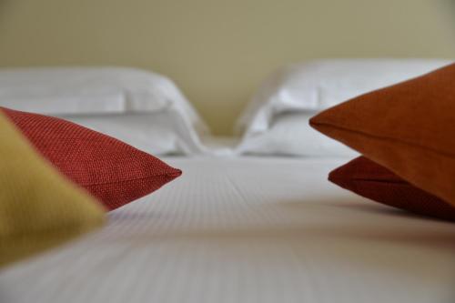 a white bed with two red pillows on it at Best Western Plus Soave Hotel in San Bonifacio