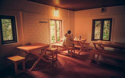 una donna seduta a un tavolo in una stanza di Ela Ecoland Nature Retreat a Munnar