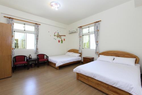 a bedroom with two beds and two chairs and windows at Kimdawn Homestay in Jinsha