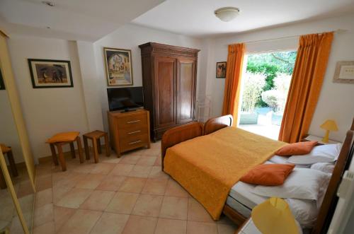 a bedroom with two beds and a television and a window at Au vallon rouge (Suite double) in Saint-Paul-de-Vence
