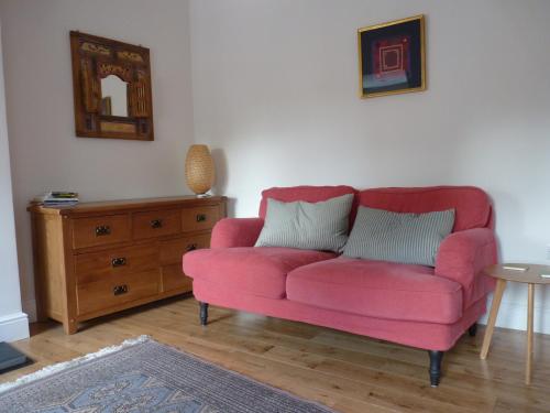 a pink couch in a living room with a dresser at Brockenhurst Apartments in Brockenhurst