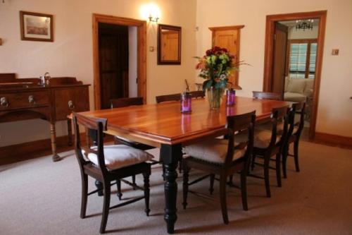 a wooden table with chairs and a vase of flowers at De Kothuize 166 in Graaff-Reinet