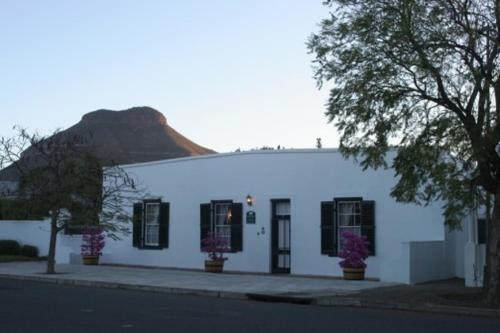 a white building with a mountain in the background at De Kothuize 166 in Graaff-Reinet