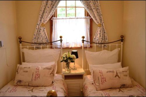 a bedroom with a bed with pillows and a window at De Kothuize 166 in Graaff-Reinet