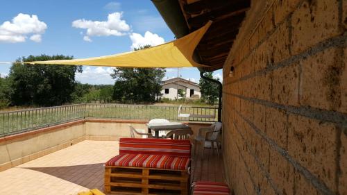 a patio with a table and chairs and a yellow umbrella at Agriturismo Podernuovo in Acquapendente