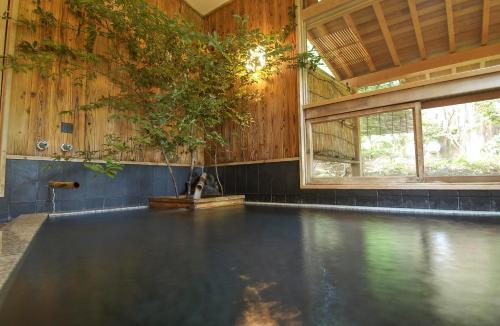 una piscina vacía con un árbol en una habitación en Hanafubuki en Ito