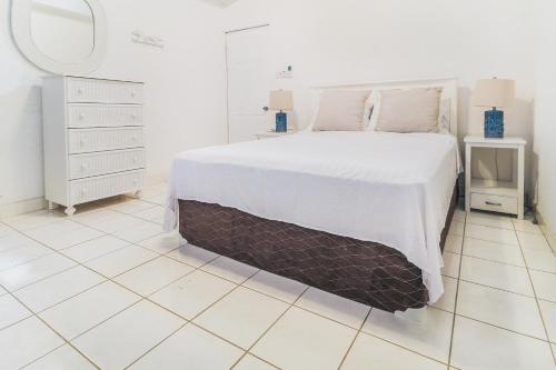 a white bedroom with a large bed and a mirror at 230 GG Rockley Barbados in Bridgetown