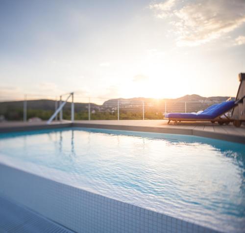 uma piscina com uma espreguiçadeira e o pôr-do-sol em One Suite Hotel em Mlini