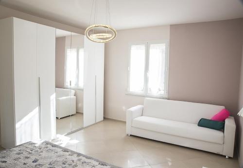 un soggiorno con divano bianco e lampadario pendente di Villa Il Roseto Redinoce a Procchio
