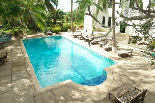 a swimming pool with chaise lounges and chairs at The Old Boma Hotel in Mtwara