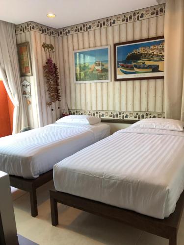 two beds in a hotel room with white sheets at Mexican Beachfront Condo in Khao Tao