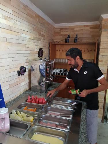 a man standing in a kitchen preparing food at Pousada Blue Viking in Praia do Frances
