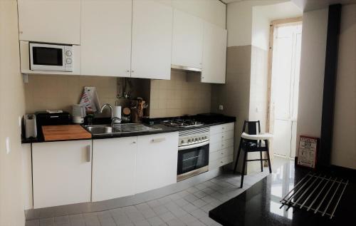 リスボンにあるCentral Lisbon Classic Apartmentのキッチン(白いキャビネット、シンク、コンロ付)