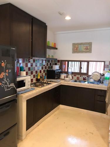 a kitchen with brown cabinets and a white microwave at Mexican Beachfront Condo in Khao Tao