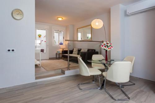 a living room with a glass table and white chairs at Apartamento Vadim in Ardales