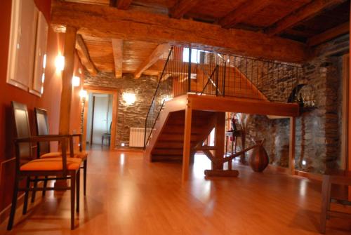 a living room with a wooden staircase and a stone wall at Masia d'en Valentí in Anserall