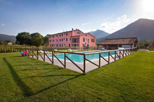 a pool in a field with a house and a building at Tenuta San Giovanni Lucca in Lucca