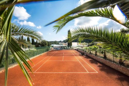 a tennis court with palm trees in the foreground at Seventeen Hotel in Valbonne