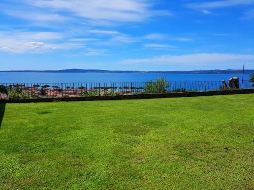 a large green field with a view of the water at Villa Isotta in Trevignano Romano
