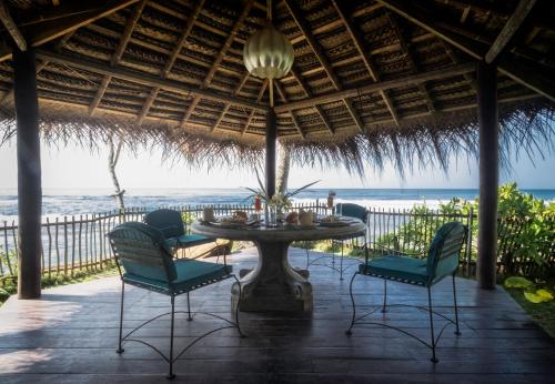 une terrasse avec une table et des chaises et l'océan dans l'établissement Satin Doll, à Unawatuna