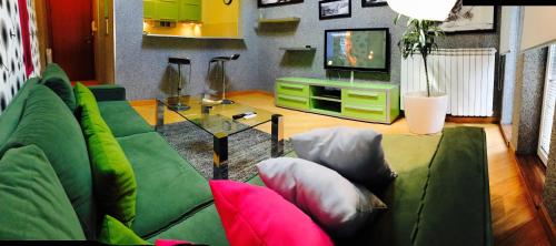 a living room with a green couch and a television at Vip apartment Beograd in Belgrade