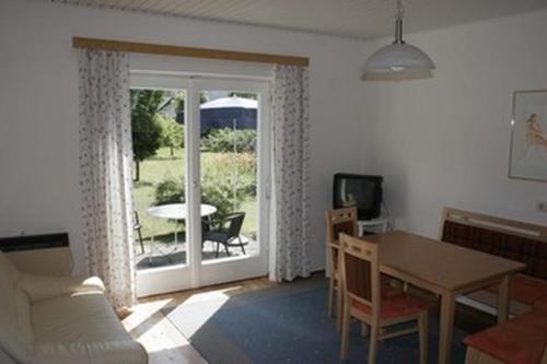 sala de estar con mesa y puerta corredera de cristal en Ferienwohnungen Benedikt en Villach