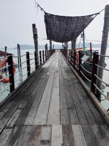 a dock with a hammock and a boat at Pangkor Home Sea Village in Pangkor