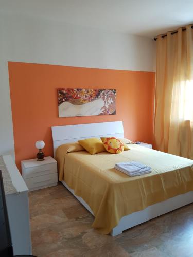 a bedroom with a bed with an orange wall at B&B Soleluna in Massa Fiscaglia