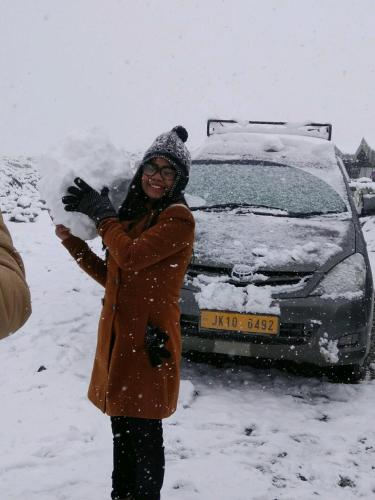a woman standing in the snow next to a car at Mystic Pangong in Spangmik
