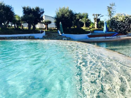 a swimming pool with clear blue water and umbrellas at Hotel de Charme Capela das Artes in Armação de Pêra